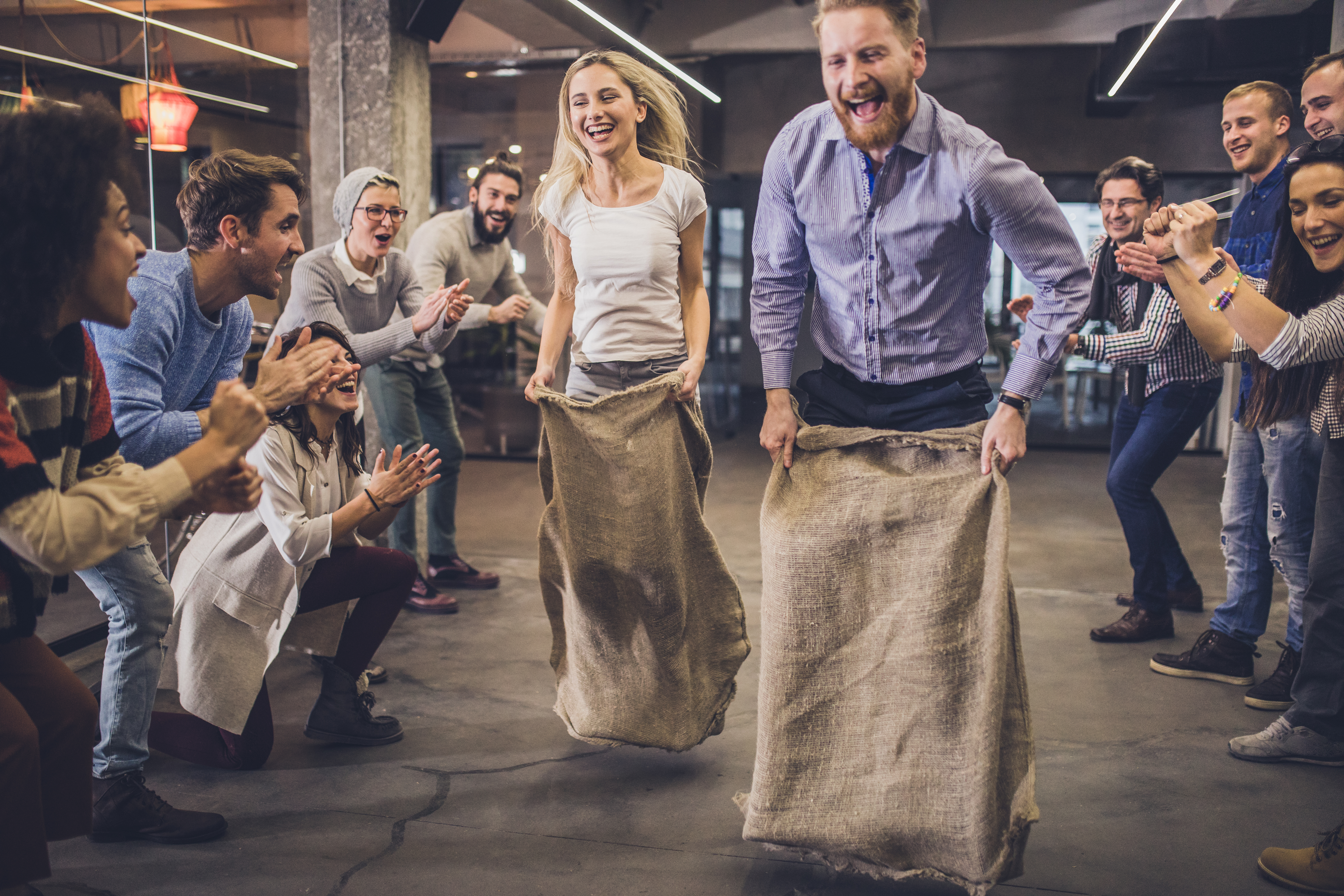 Large group of happy entrepreneurs having fun on a sack race in the office,