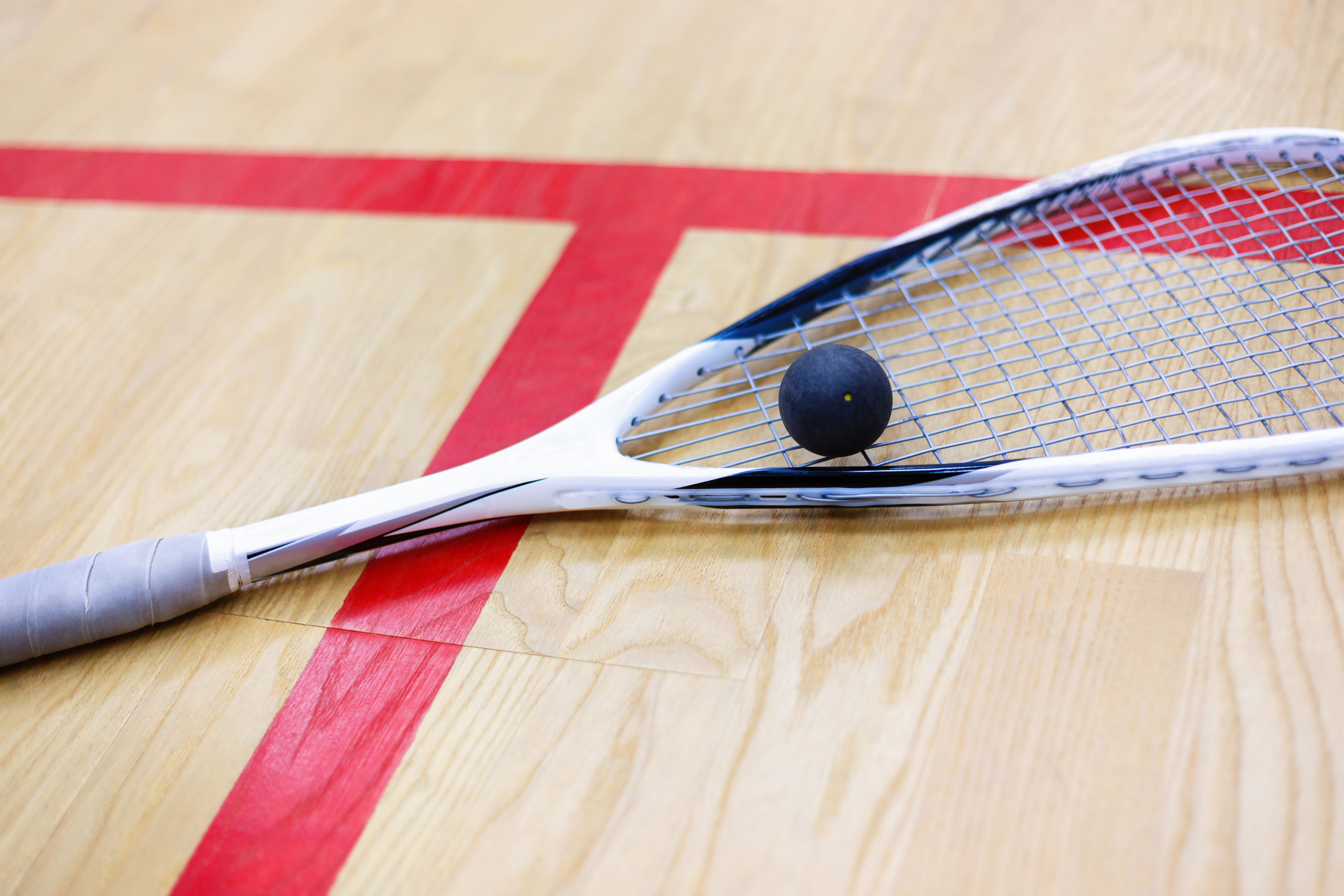 Squashracket met balletje op  squashvloer