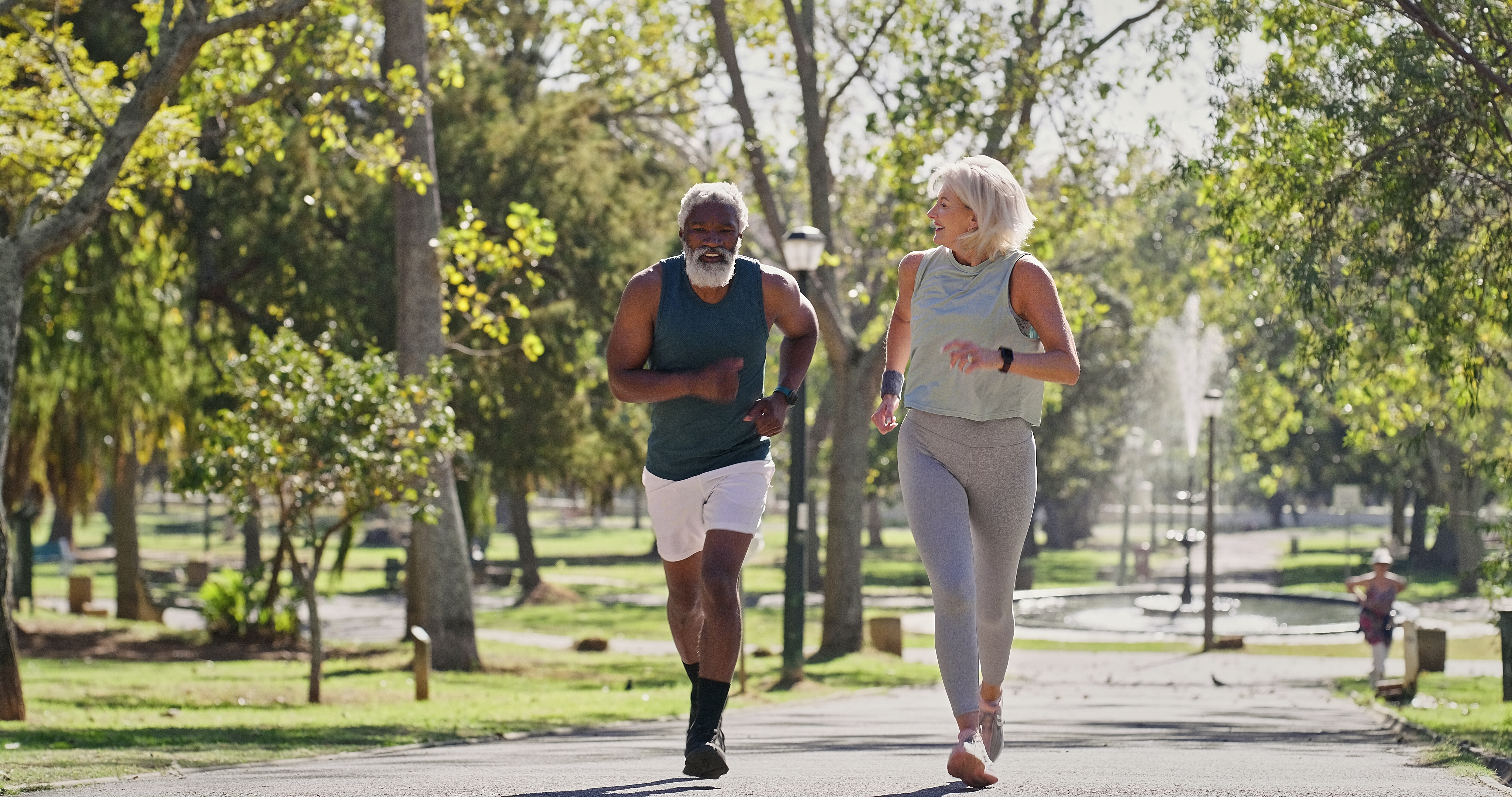 Fitness, senior people or running in park for wellness, cardio exercise or training in retirement. Elderly couple, smile or outdoor for workout with support, motivation or friends on path with energy