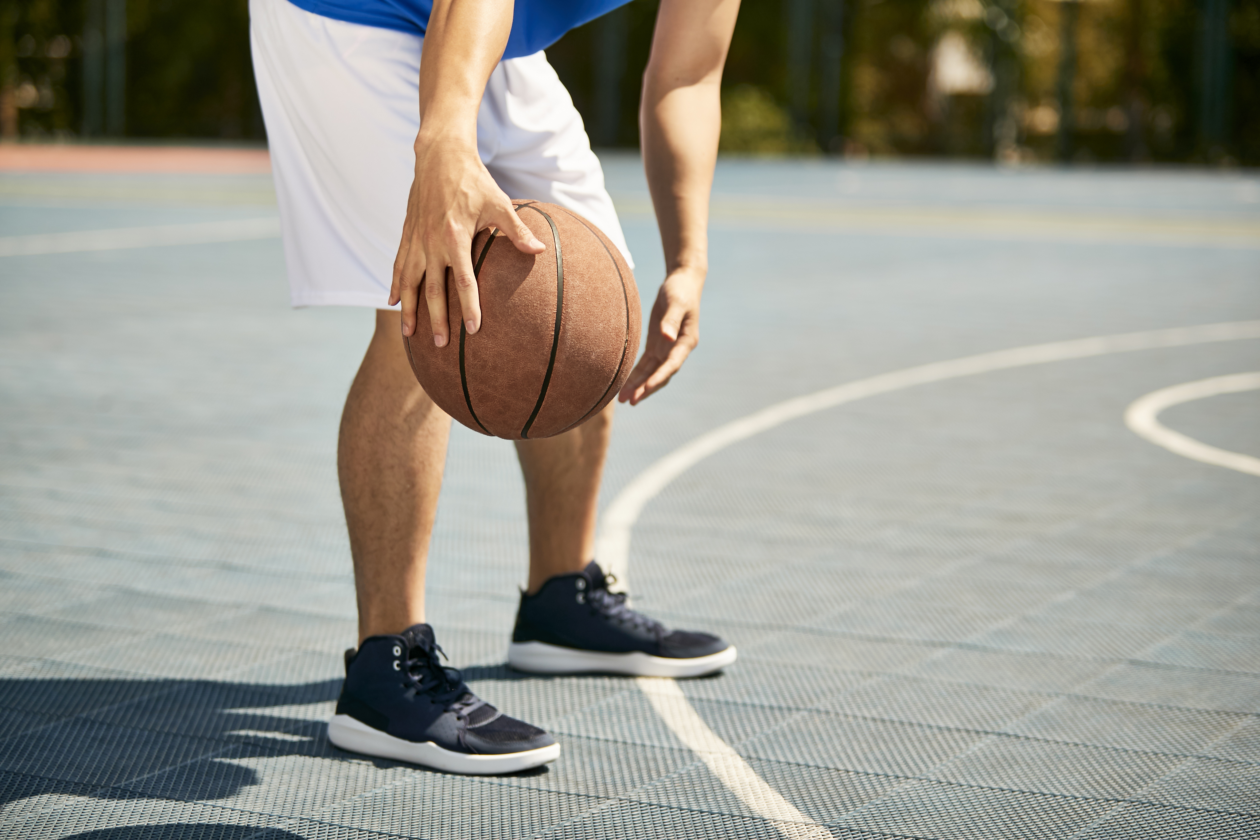 jonge basketter dribbelt met bal, enkel benen zichtbaar