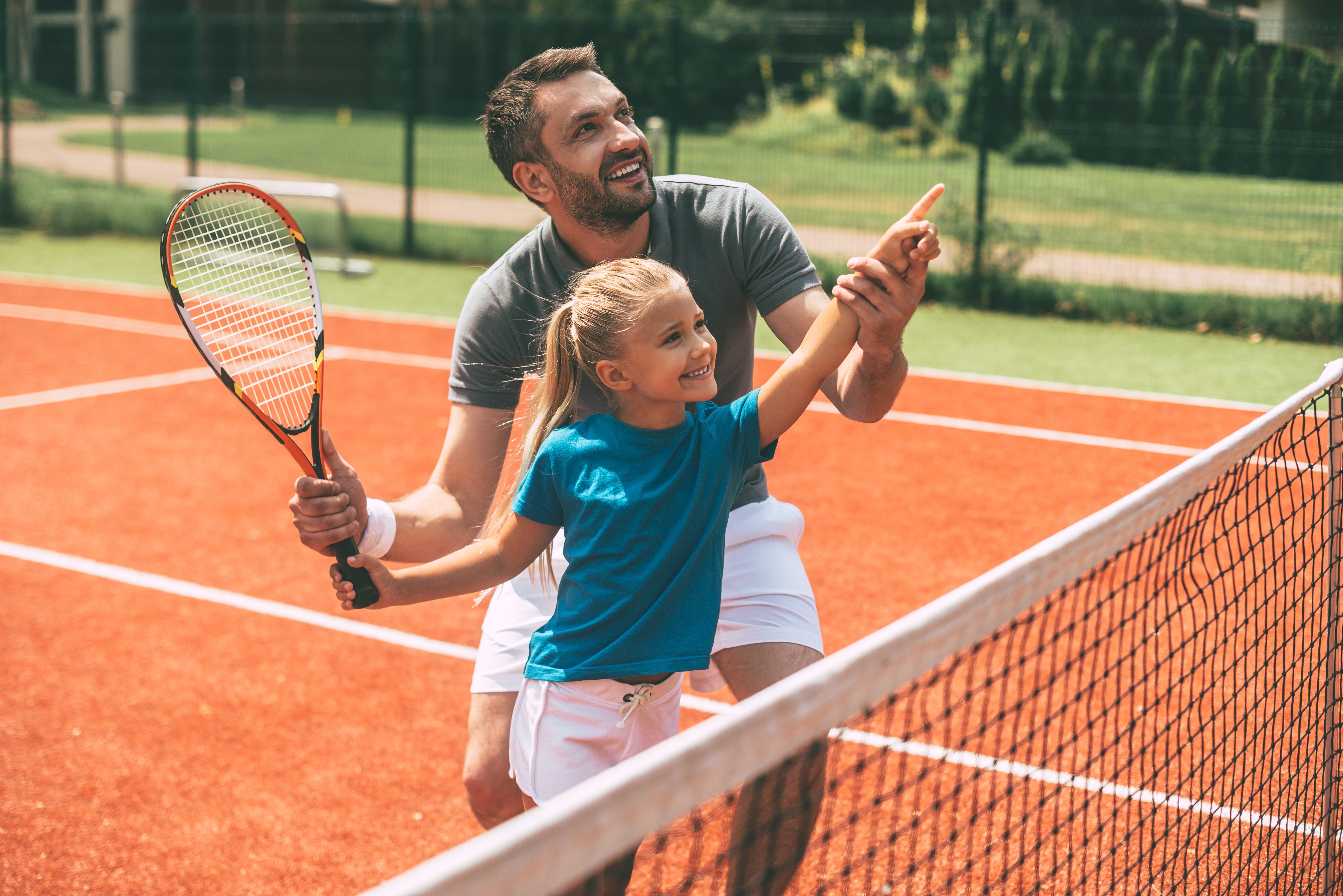 Meisje met coach op gravel tennisveld