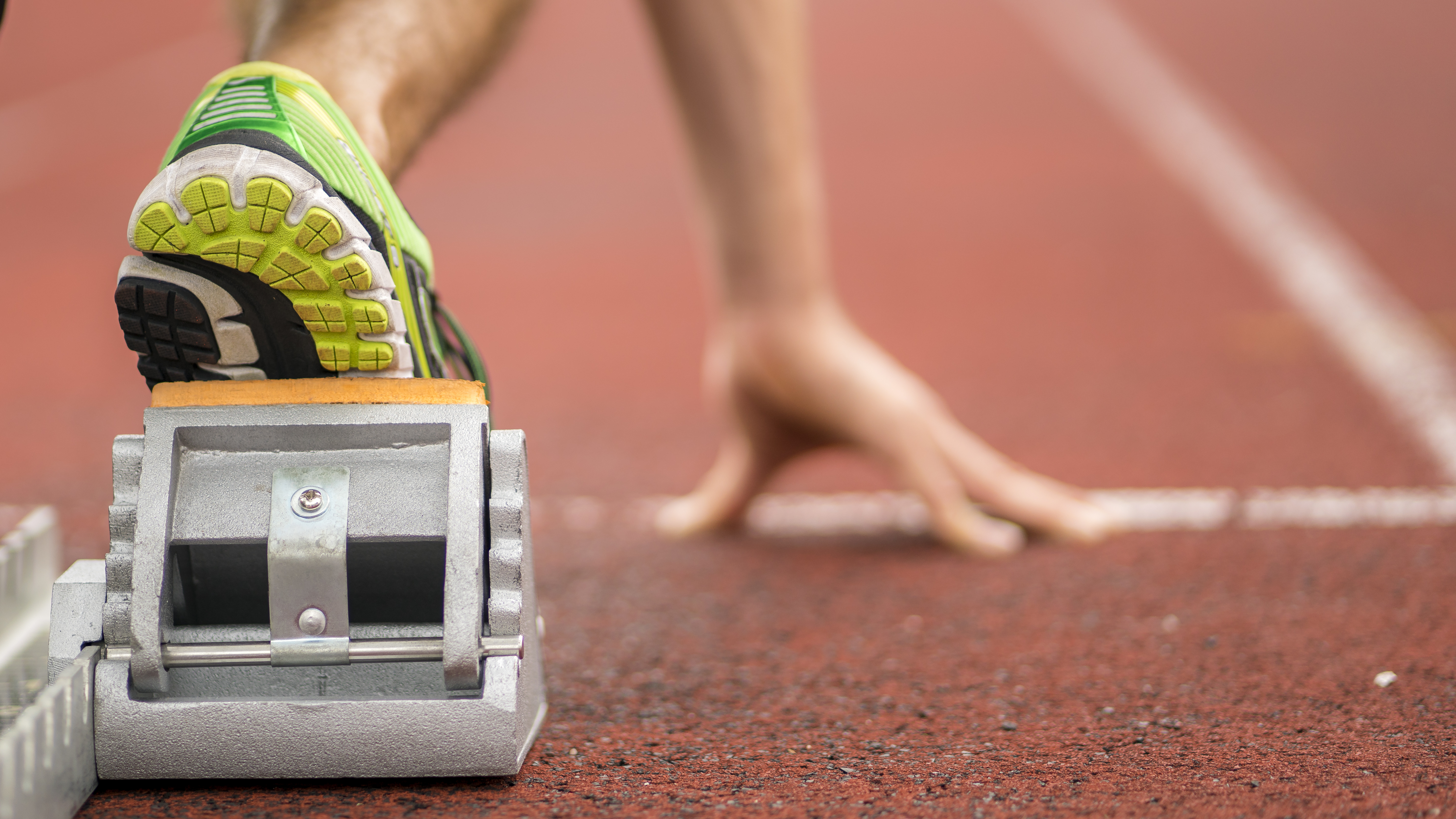 Close-up van hand en voet in startblok