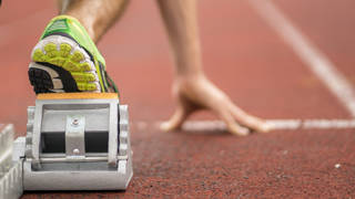 Close-up van hand en voet in startblok
