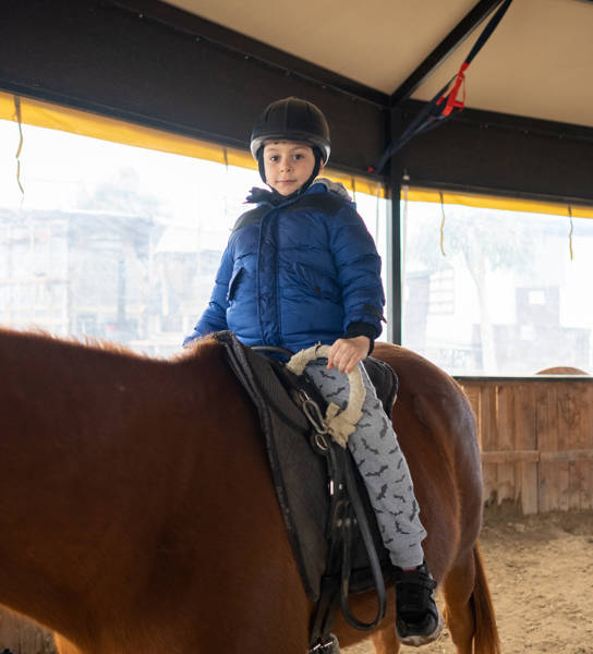 Little boy riding training horse