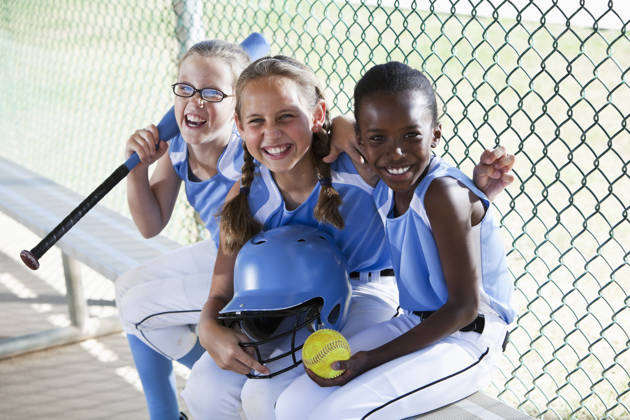 Multi culturele meisjes van baseballteam zitten in dug-out.