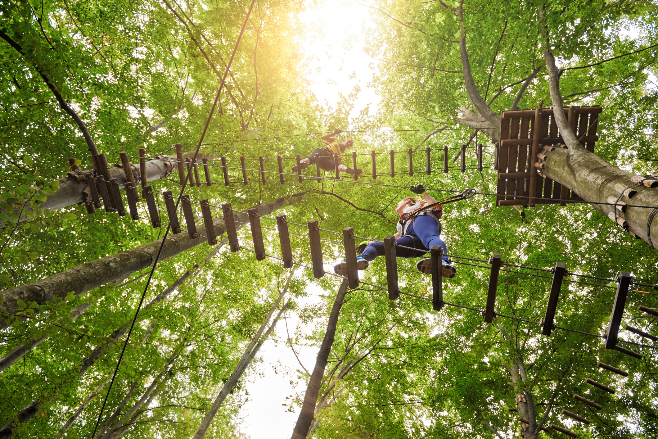 low angle view of three friends in adventure park climbing on suspension bridge.summer day.
