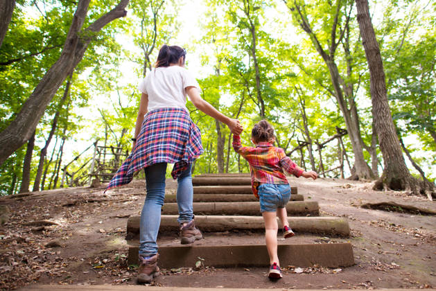 Mother and daughter are up the stairs in the woods hand in hand