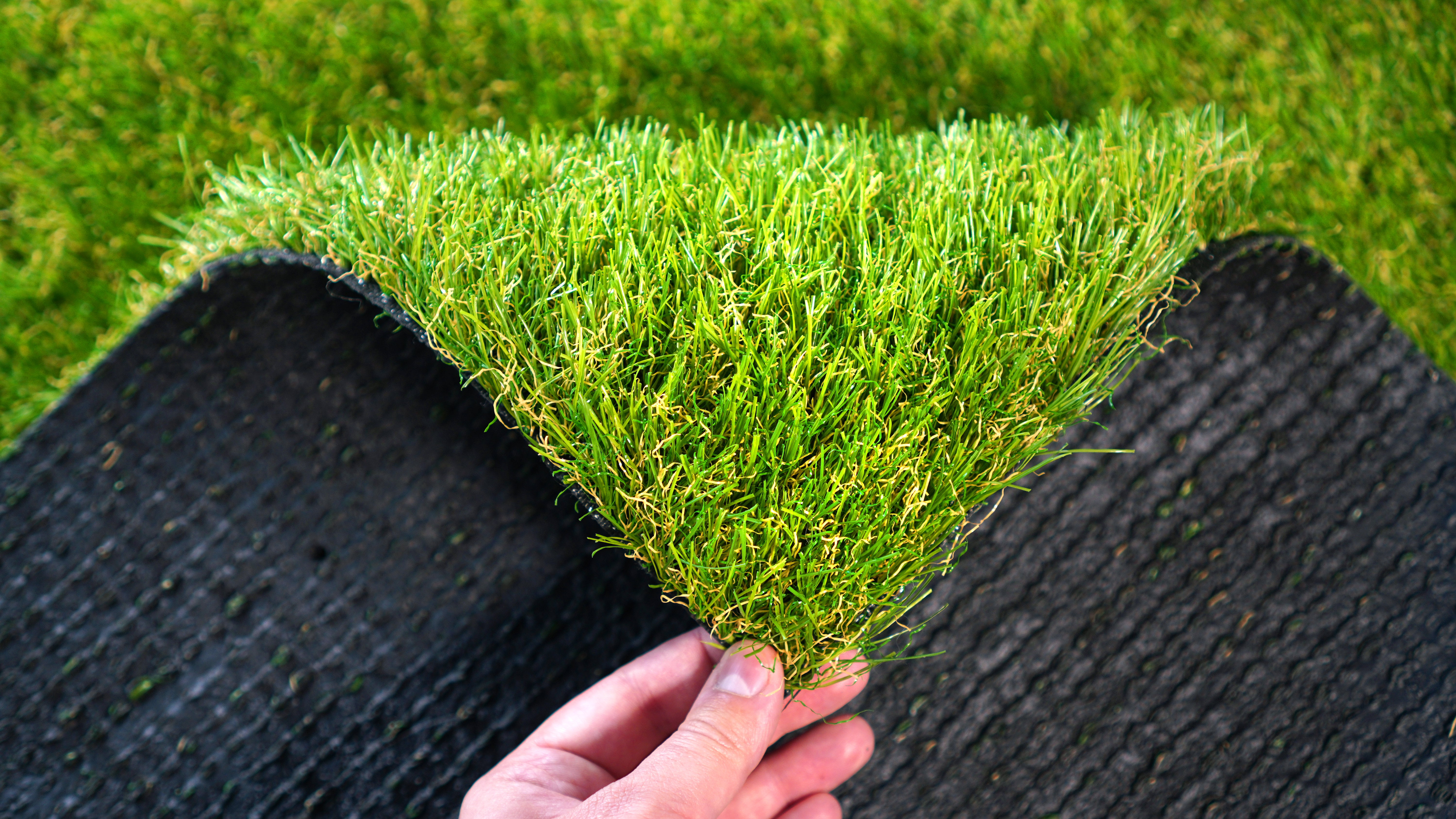 Hand houdt stukje kunstgras vast