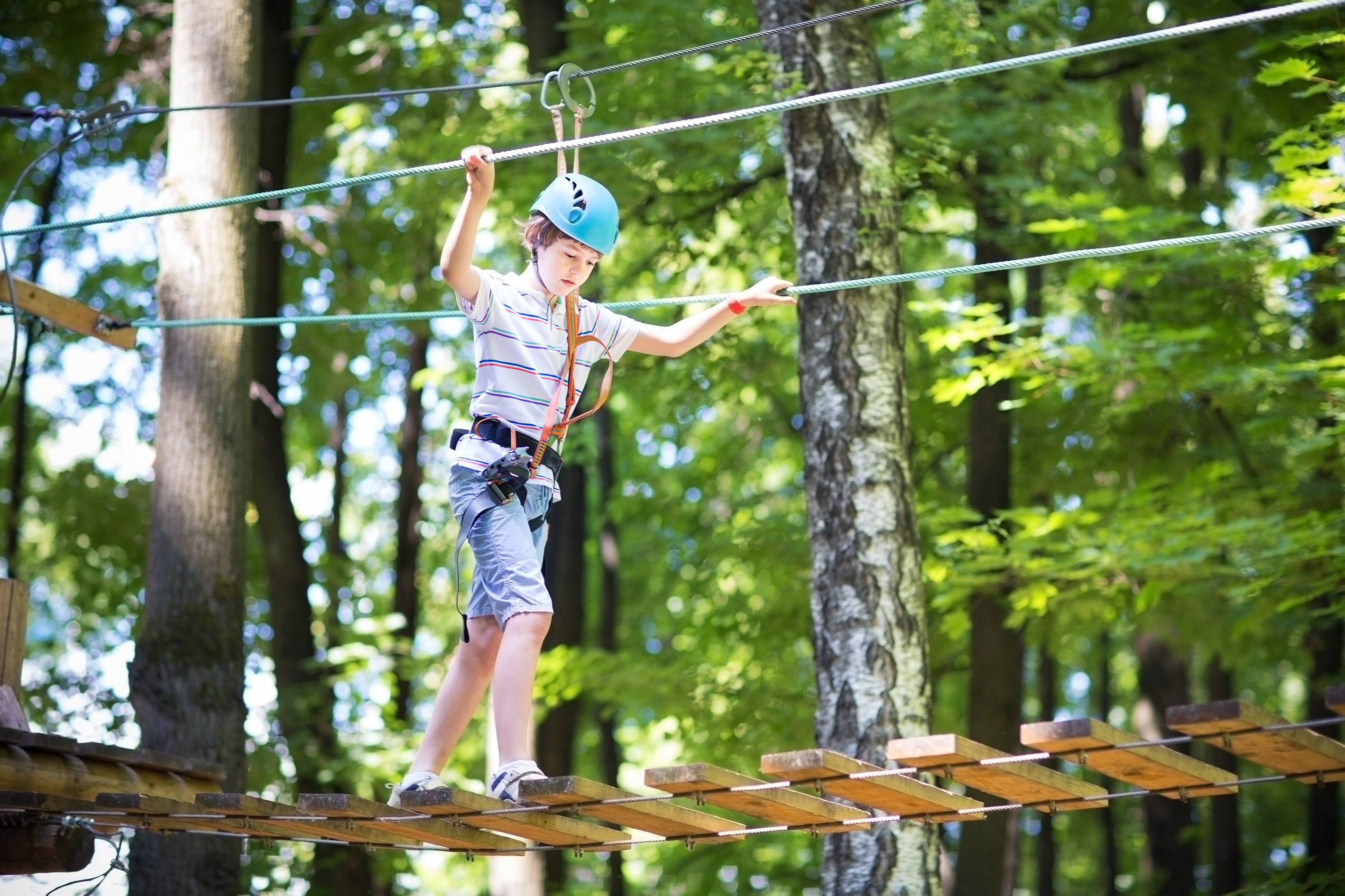 Cute school boy enjoying a sunny day in a climbing activity park