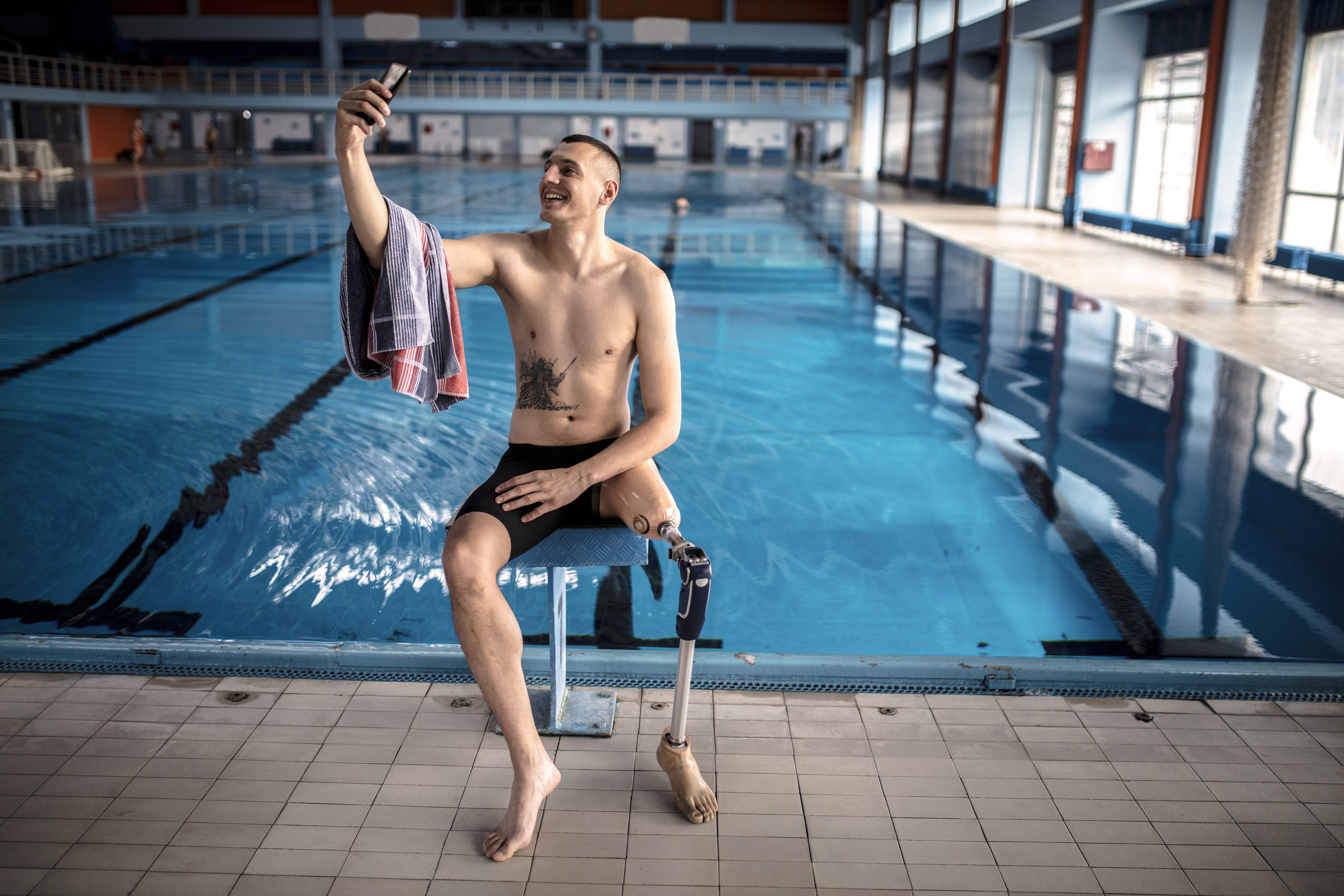 Zwemmer met prothese aan been maakt selfie voor het zwembad